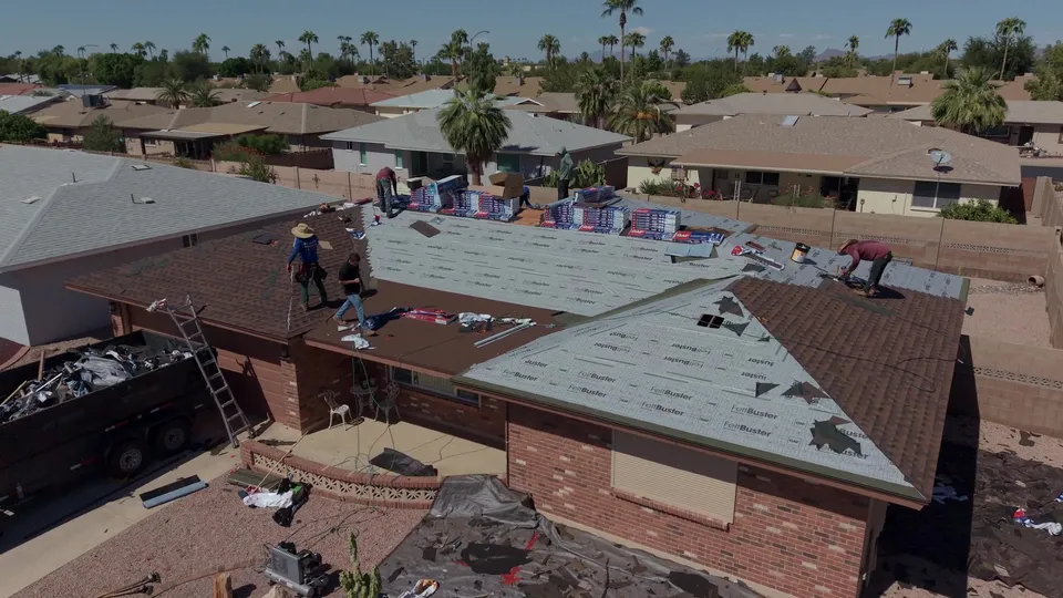 Crew installing new shingles across the same roof