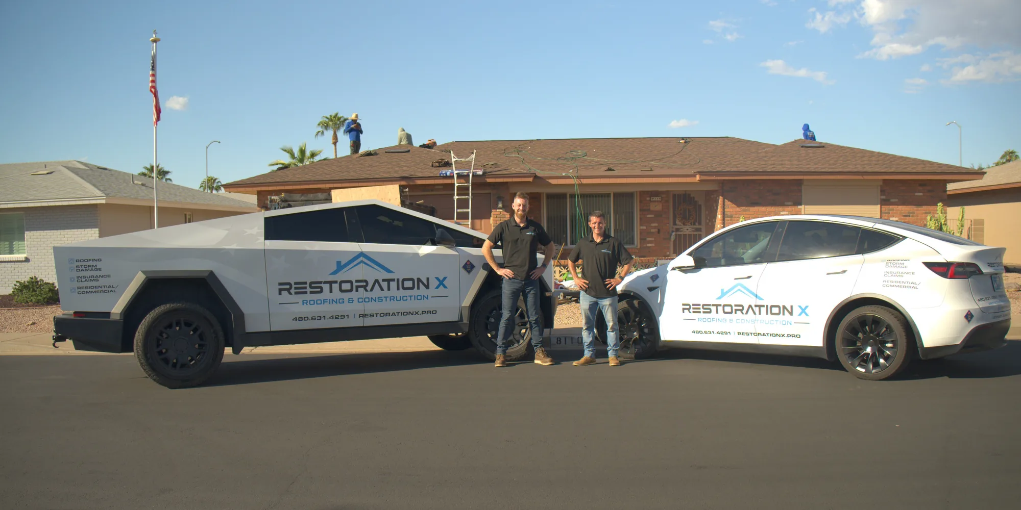 Grant Varley and Taylor Merrell, owners of Restoration X, standing between the company trucks at a job site